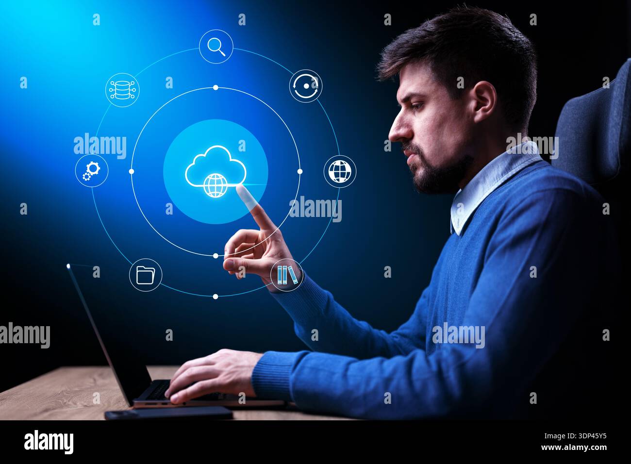 Young man using laptop for cloud computing in a dark room Stock Photo