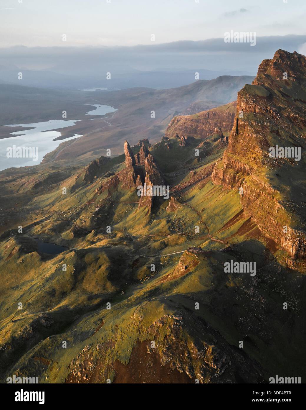 Aerial view of rugged, sun-kissed cliffs meet the soft, misty horizon ...