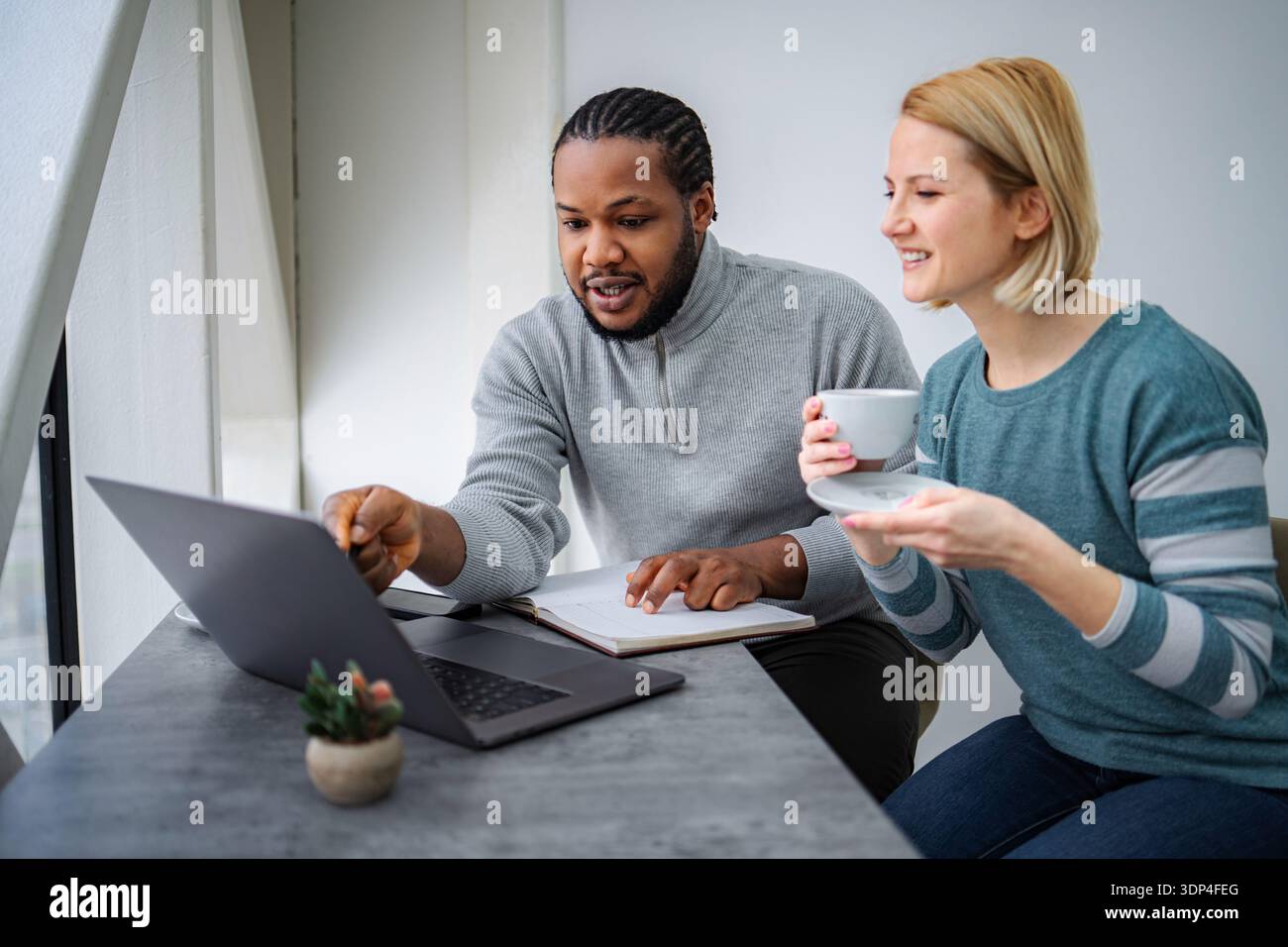 Diverse colleagues collaborating on laptop in modern office space Stock Photo