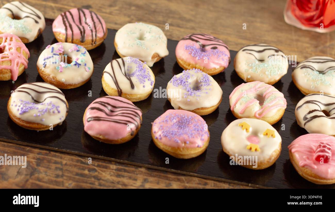 Mini donuts covered in chocolate on a black background. Stock Photo