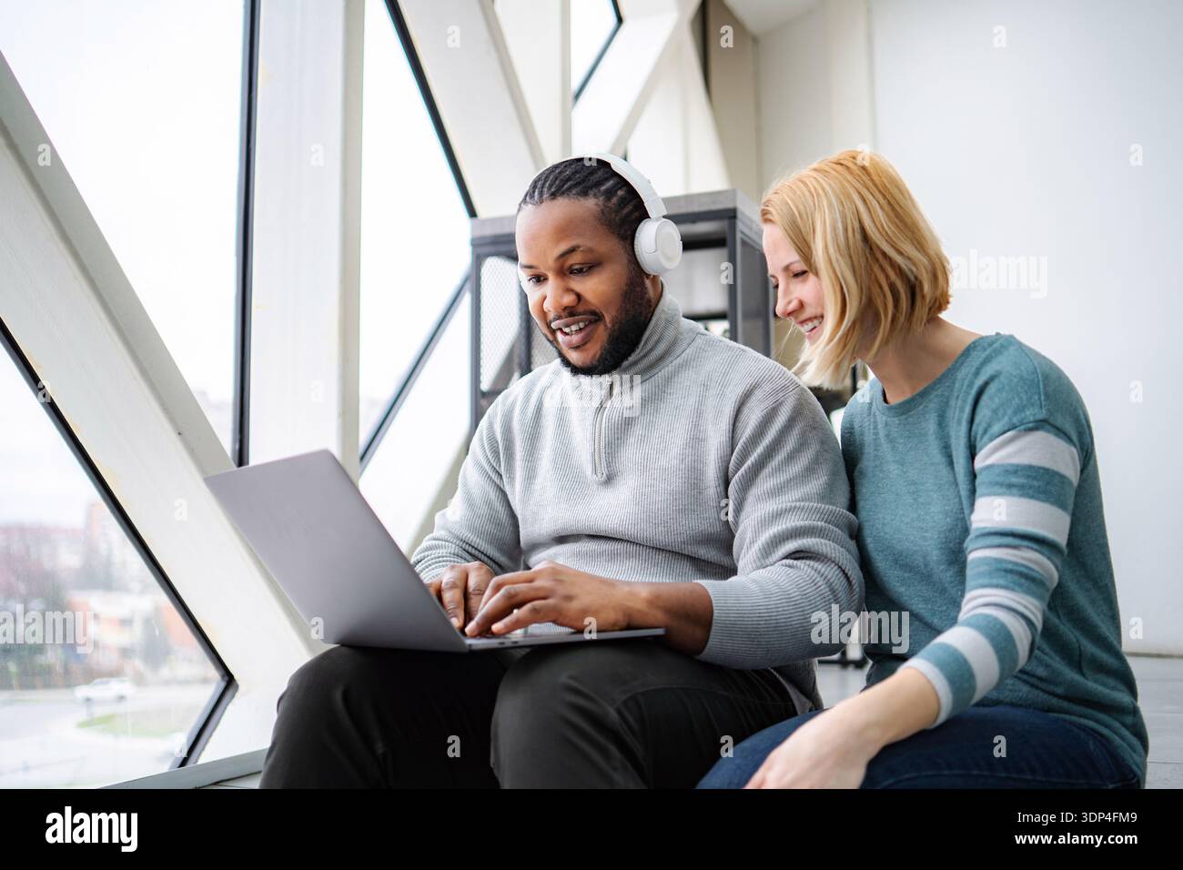 Diverse colleagues collaborating on laptop in creative office Stock Photo