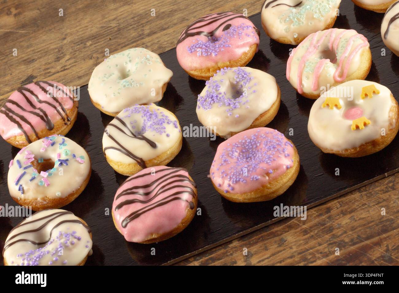 Mini donuts covered in chocolate on a black background. Stock Photo