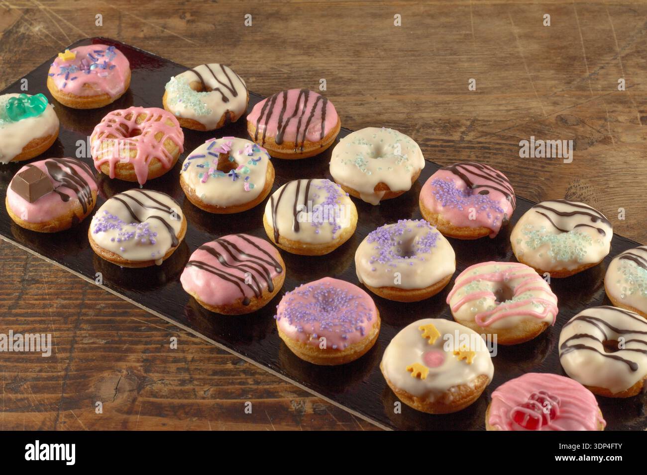 Mini donuts covered in chocolate on a black background. Stock Photo