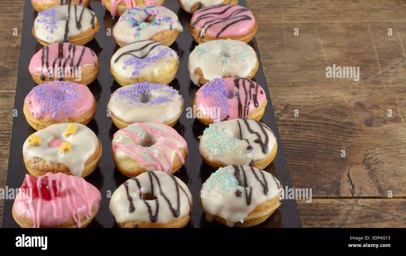 Mini donuts covered in chocolate on a black background. Stock Photo