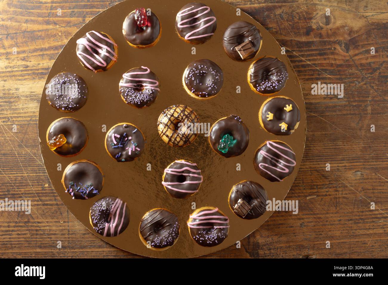 Mini donuts covered in dark chocolate on a gold background. Stock Photo