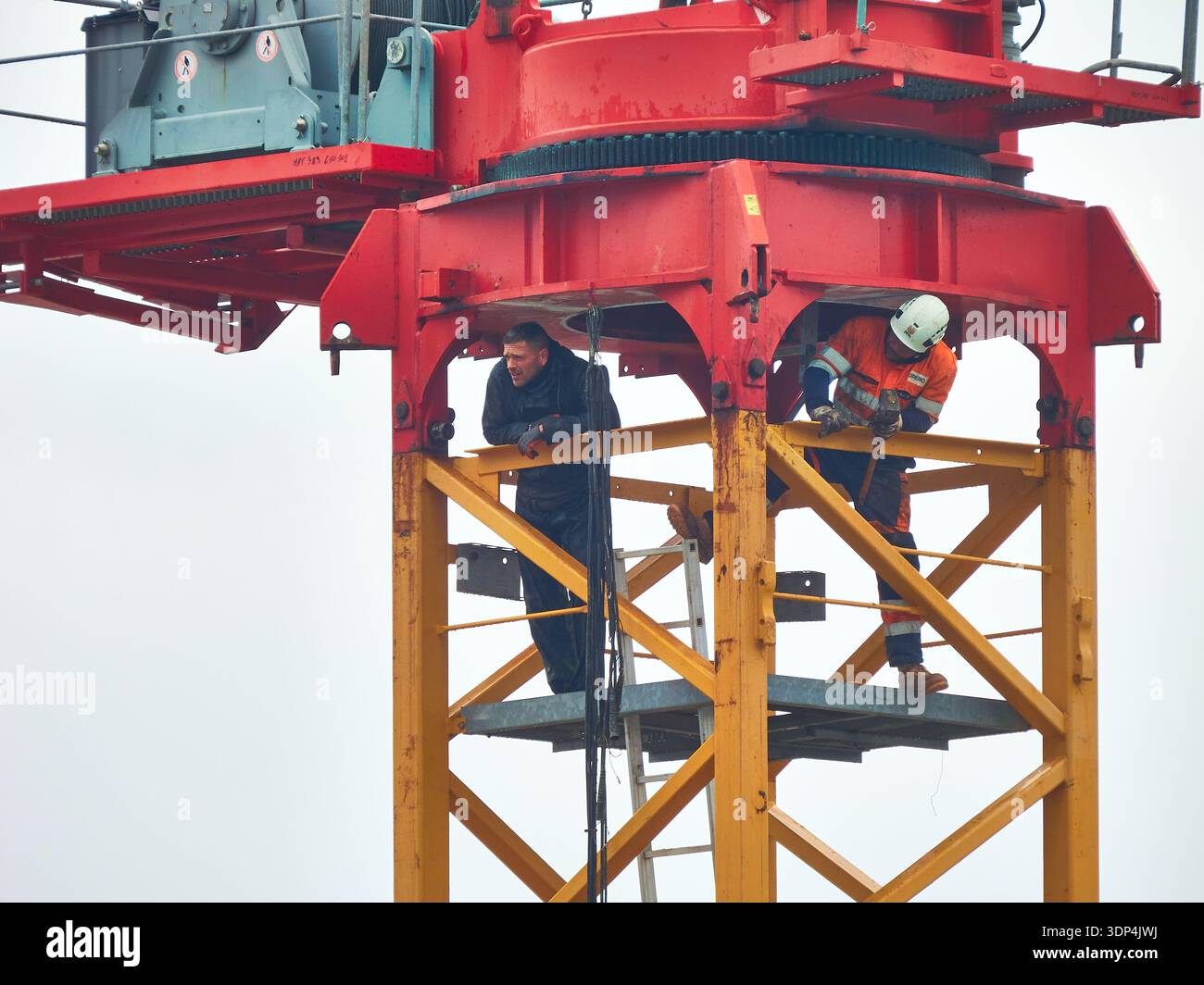 Construction Workers On Crane Tower Inspecting Structure With Safety Gear And Teamwork At Height Stock Photo