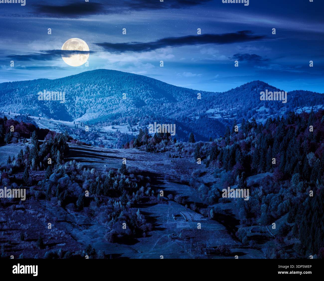 rural area in mountains autumn landscape at night. beautiful countryside scenery with rolling hills under dark sky in full moon light. backdrop for fi Stock Photo