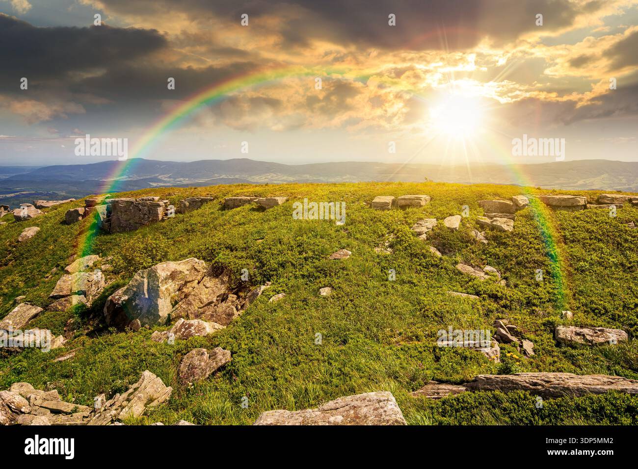 grassy alpine meadow in carpathian mountain landscape at sunset. sharp rocks and huge boulders among green grass on rolling hills in evening light. op Stock Photo