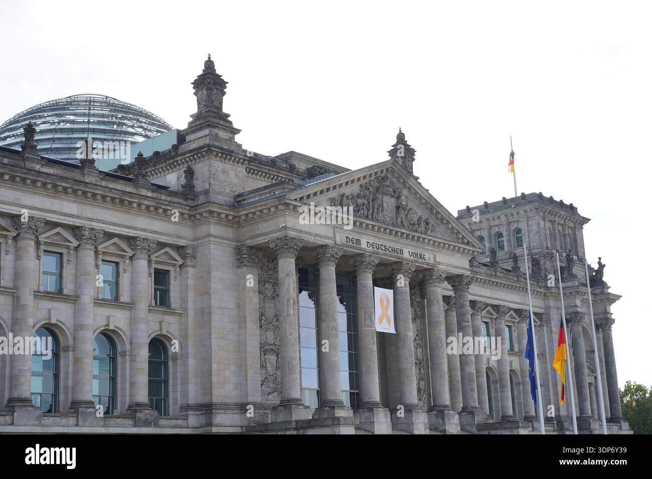 Berlin, Germany - October 7, 2024: Reichstag building with yellow ribbon and flags at half-mast for the anniversary of the Oct 7 terror attacks. Stock Photo