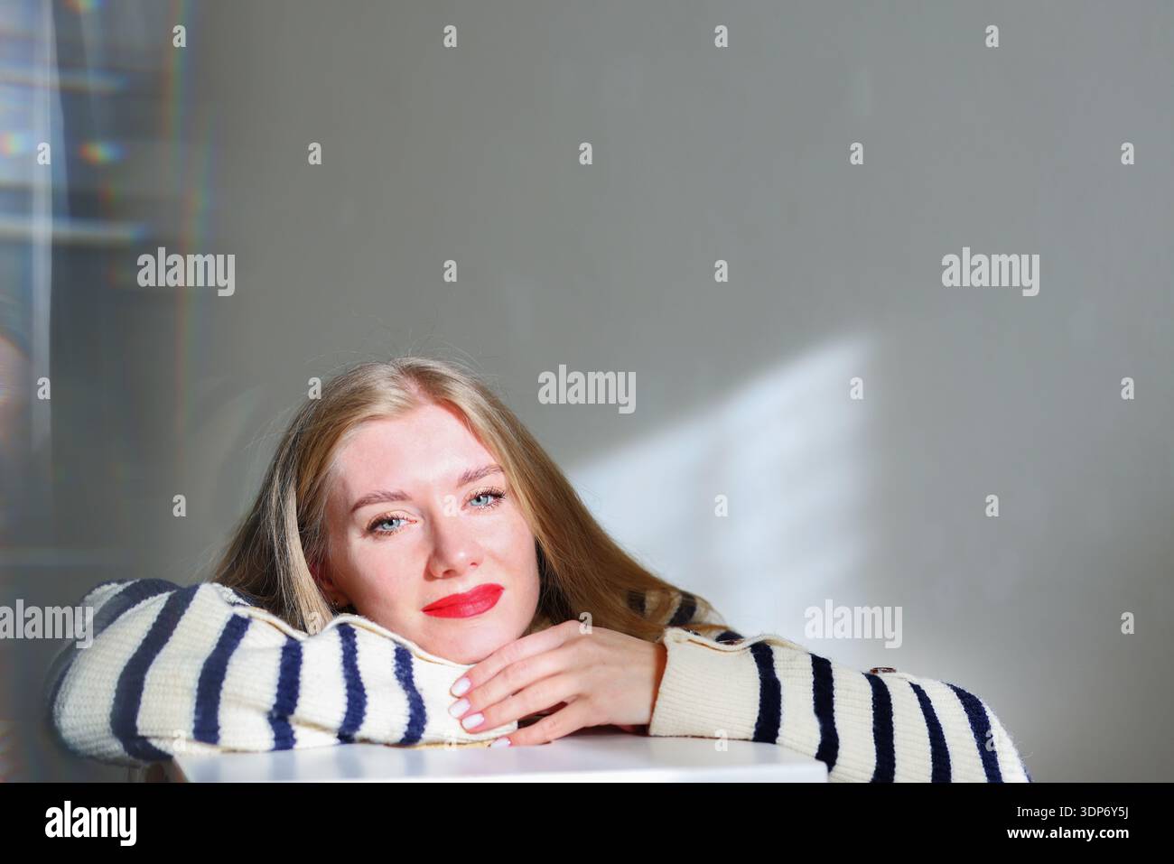 Thoughtful blonde woman with red lips relaxing indoors, copy space Stock Photo