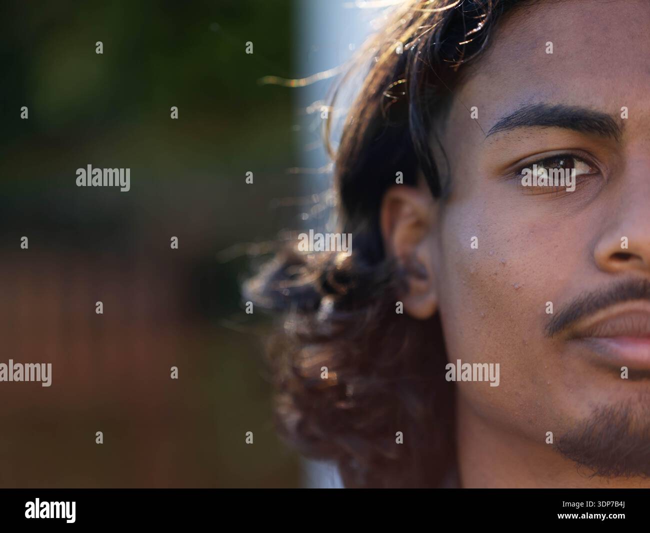 Man facing camera showing right-face closeup and wavy hair in backyard ...