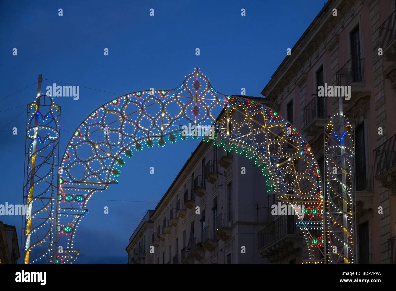Illuminated *Luminarie* street archway at twilight. Traditional decorative light installation used during Italian religious festivals (*festa patronal Stock Photo