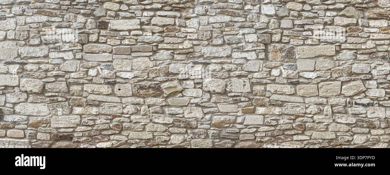 Rough stone wall background featuring natural texture and ancient masonry construction Stock Photo