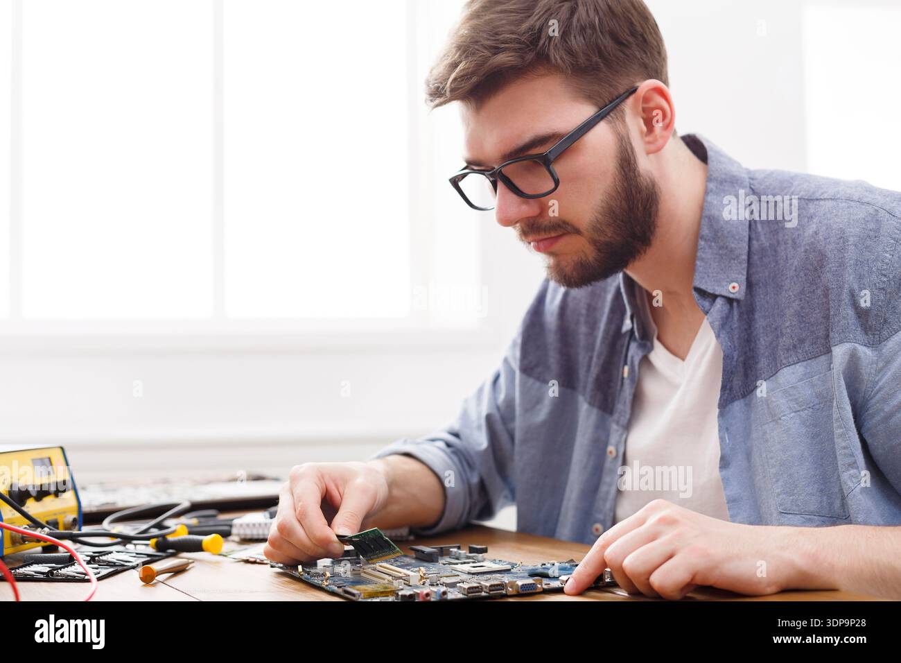 Changing Components on a Circuit Board in a Workshop During Daylight Hours Stock Photo
