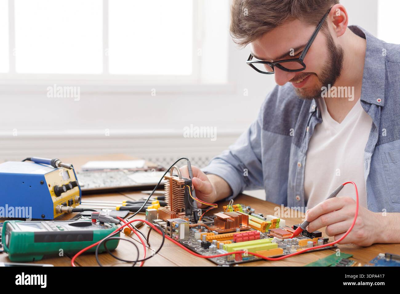 Man Working on Circuit Board With Tools and Equipment in Workshop Setting Stock Photo