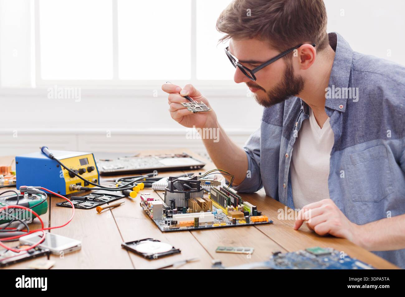 Technician Repairs Motherboard During Electronics Project in Workspace With Tools and Devices Stock Photo