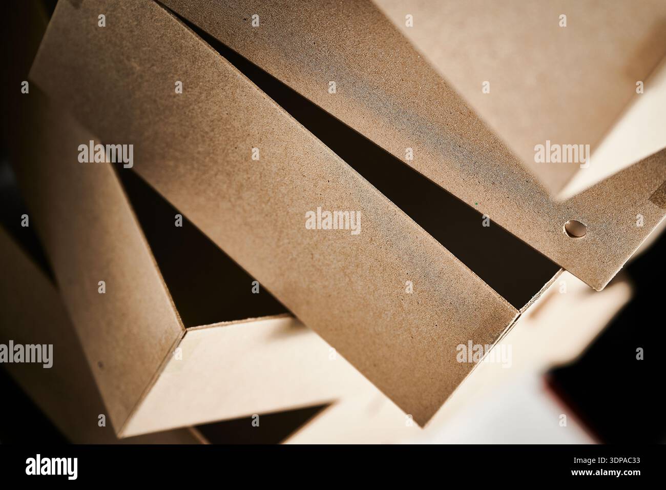 Cardboard box blanks stacked in a cardboard box manufacturing facility ready for assembly and packaging in the production process Stock Photo