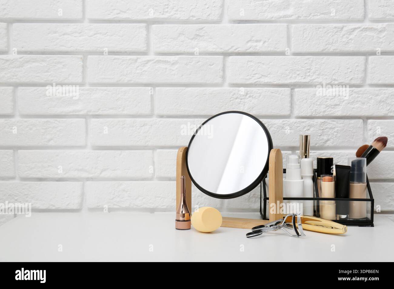 Mirror, makeup brushes and different cosmetics on table in room Stock Photo