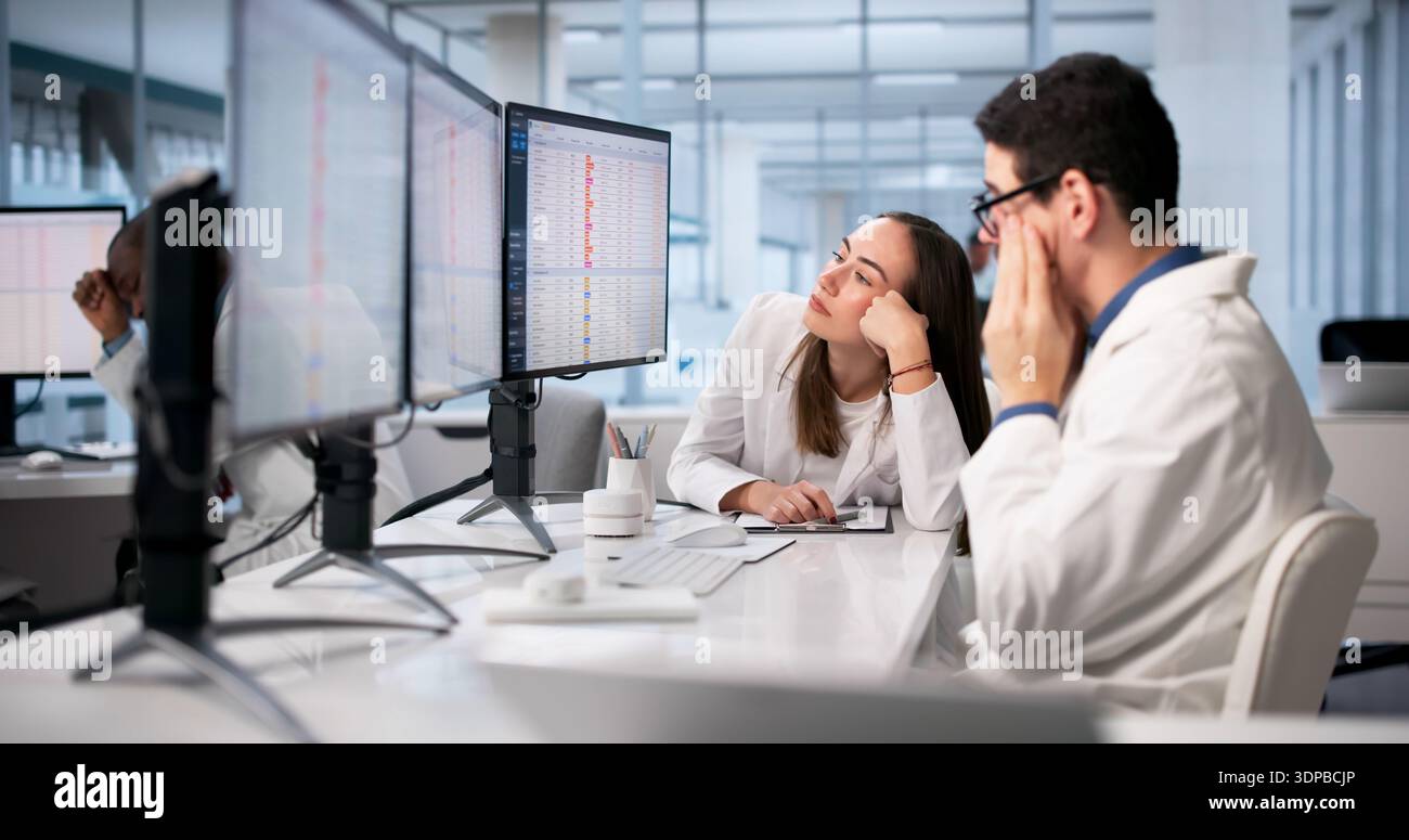 Doctors In Hospital Using Spreadsheets And Medical Codes, Feeling Stressed. Stock Photo