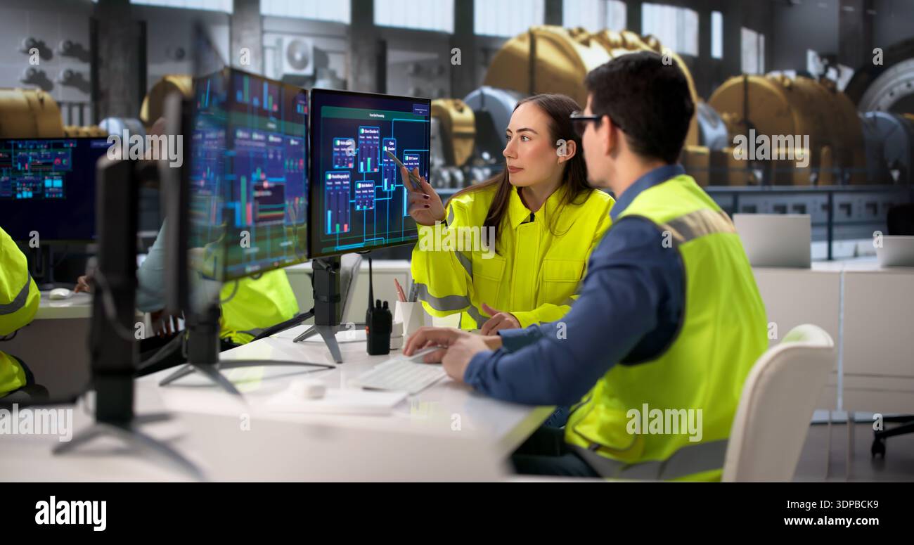 Engineers Operating Multiple Screens At Power Plant In Desktop Computer. Young Operator Using System In Diverse Group Stock Photo