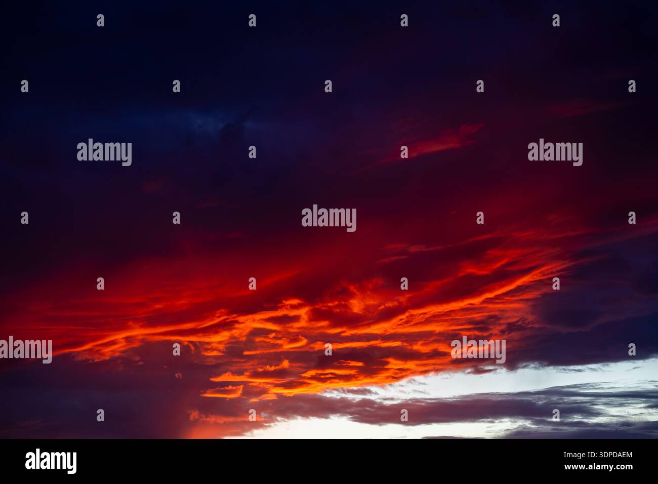 Intense red and orange sunset clouds burning through a dark dramatic sky Stock Photo