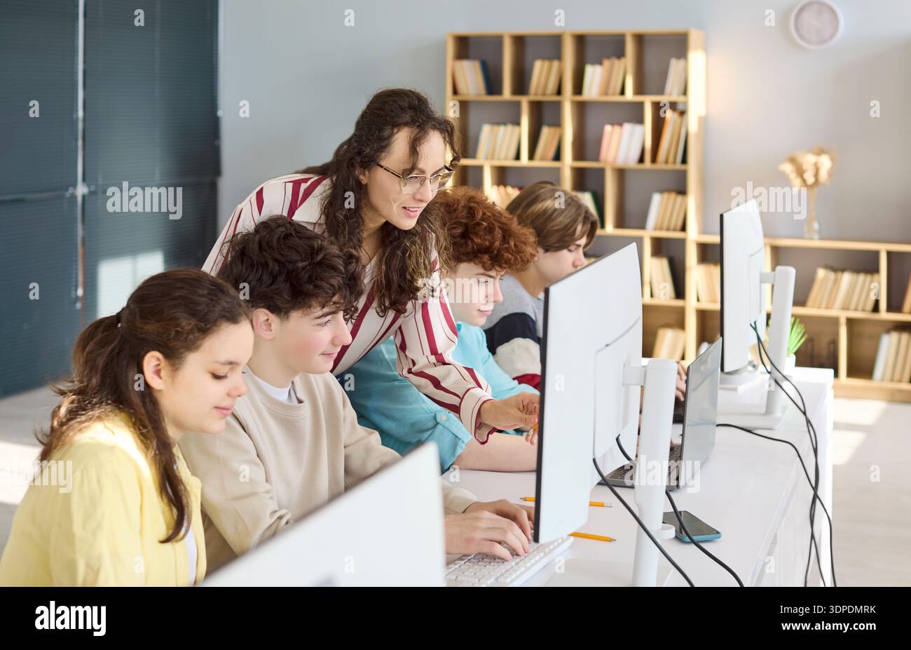 High school students programming with teacher guidance in bright computer lab Stock Photo