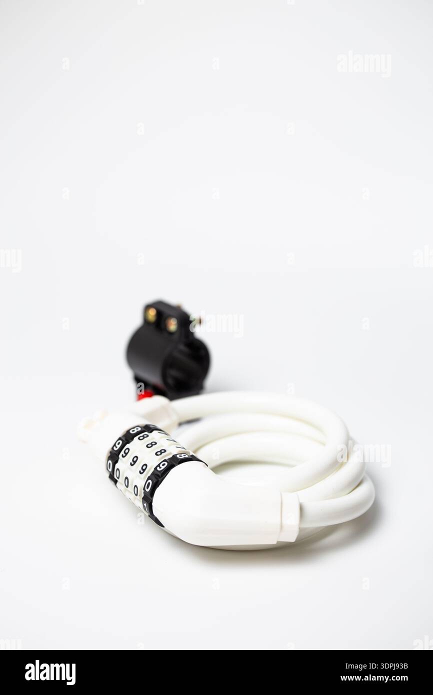 White combination coiled cable lock with mounting bracket for bicycle frame on white background. Stock Photo