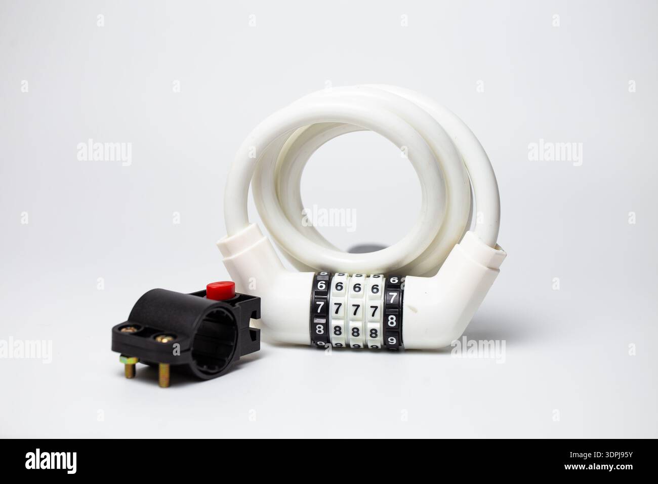 White combination coiled cable lock with mounting bracket for bicycle frame on white background. Stock Photo