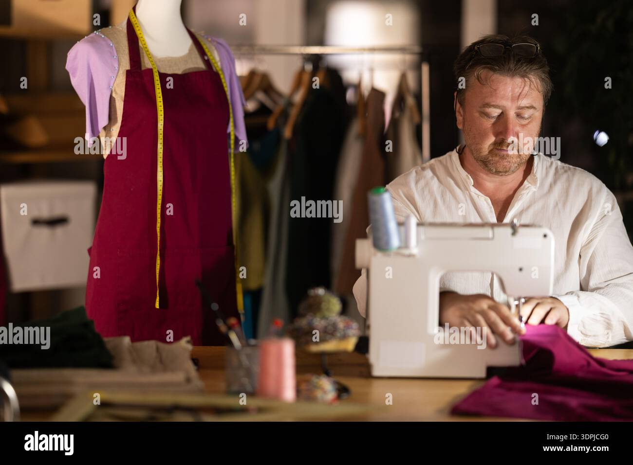 Middle-aged male dressmaker working with sewing-machine Stock Photo