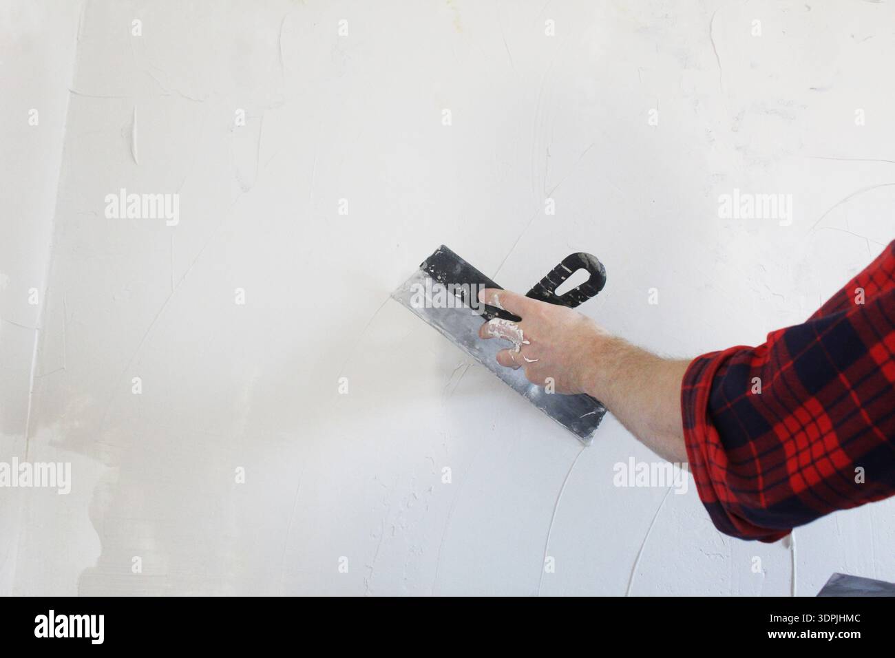 Master puttying wall with spatula close-up. Stock Photo