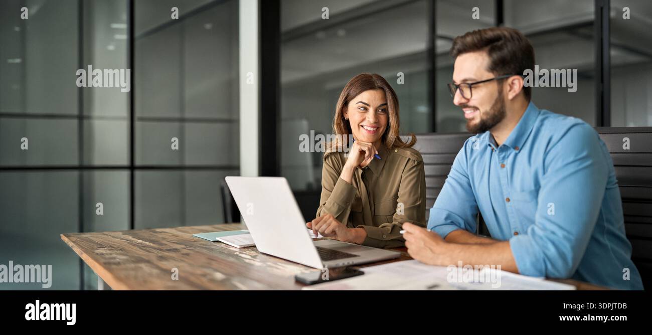Two happy professional colleagues talking at meeting using laptop computer. Stock Photo