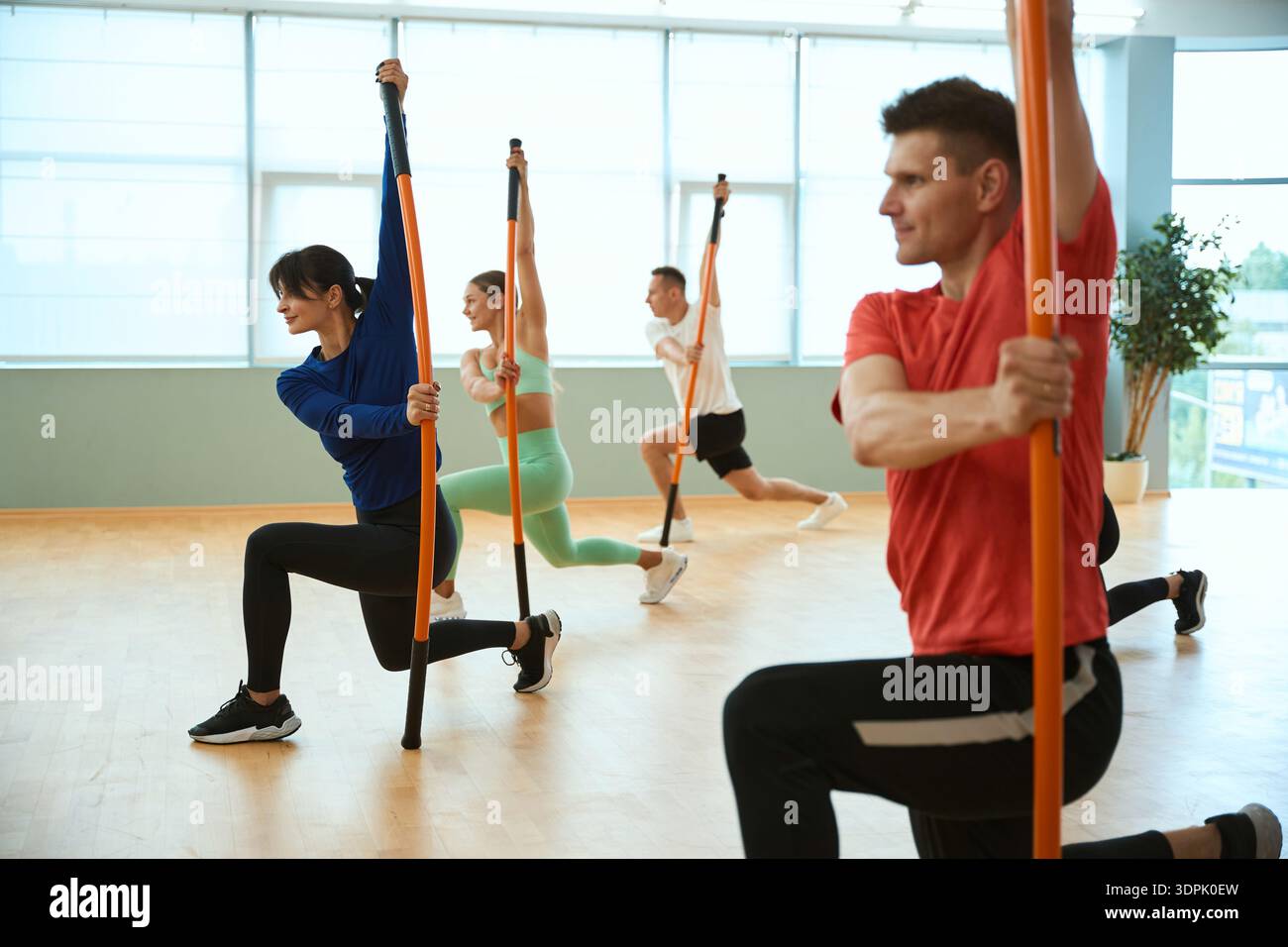 Group of people doing fitness under the guidance of an experienced coach with gymnastic sticks Stock Photo