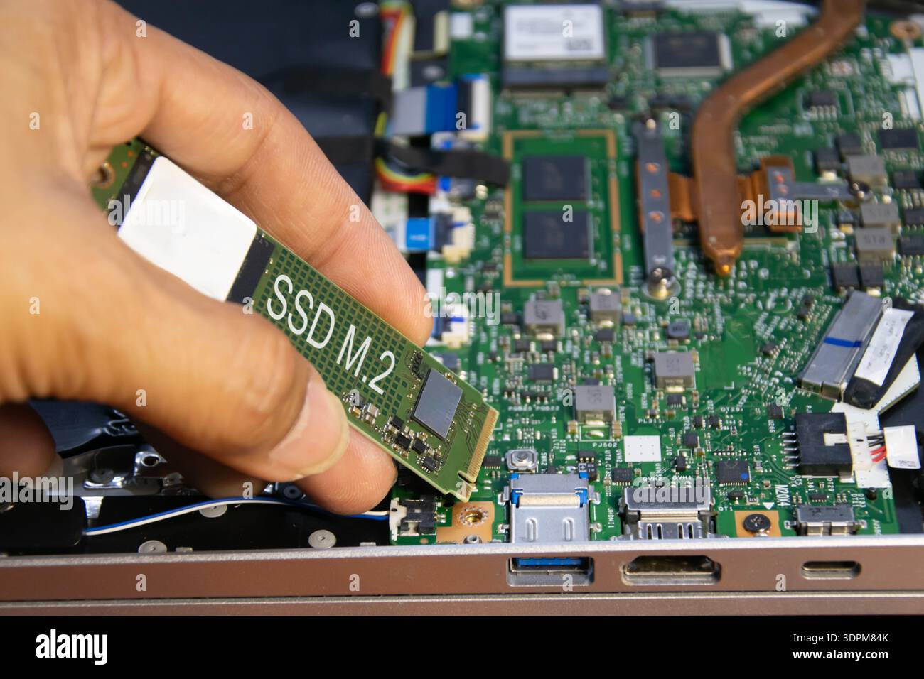 The technician is installing an M.2 hard drive. Stock Photo