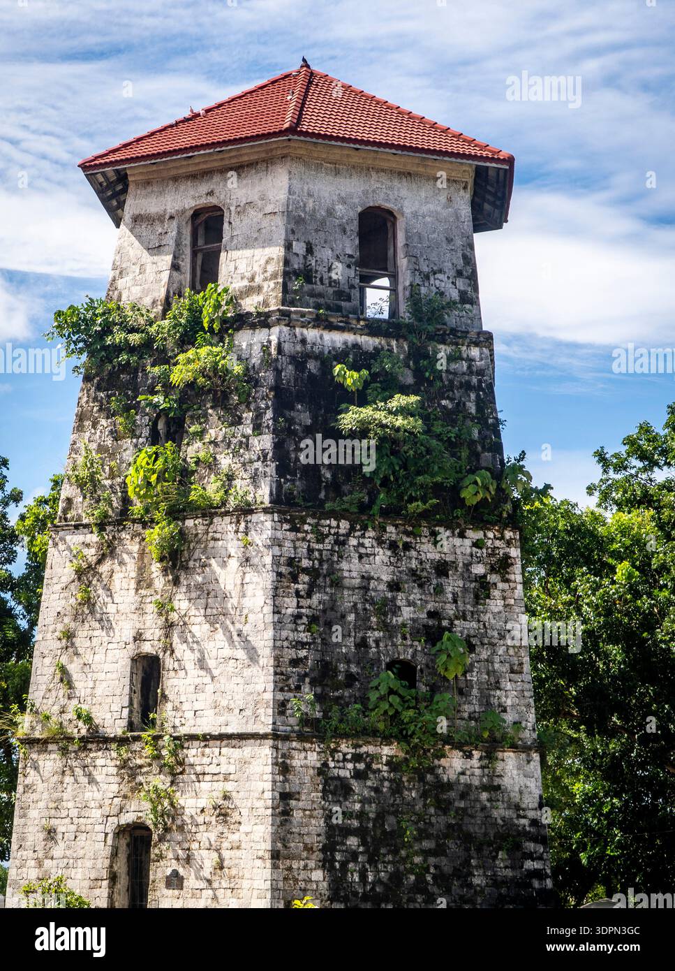 Old stone watchtower with red tiled roof, vines and greenery climbing ...