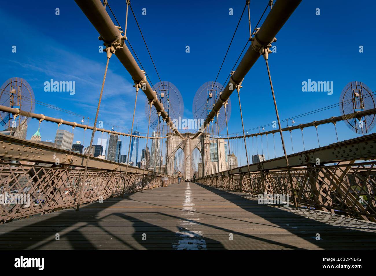 Low angle symmetrical view of the Brooklyn Bridge pedestrian walkway with Manhattan skyline in the background. Iconic New York City landmark represent Stock Photo