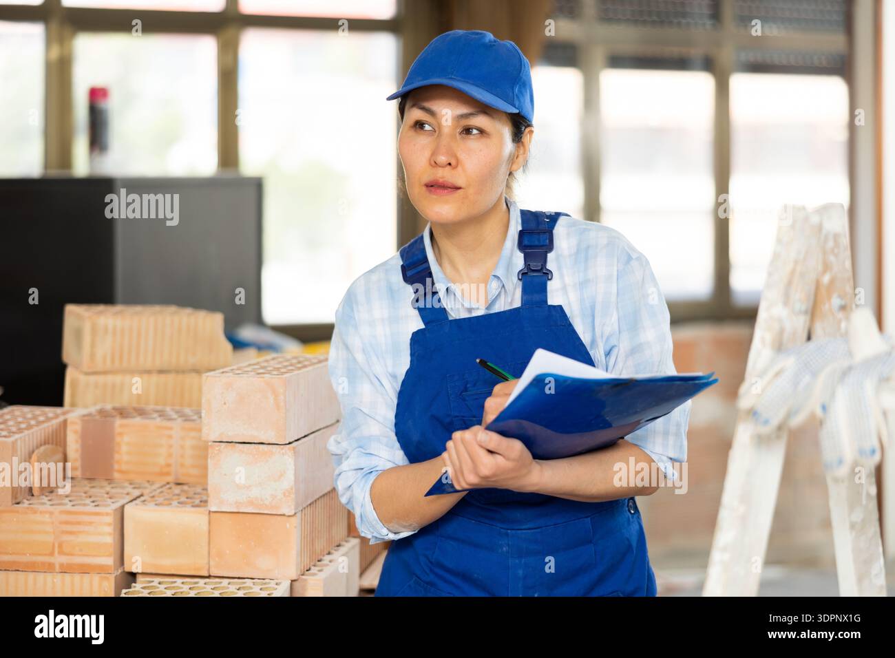 Woman making notes on indoor construction site Stock Photo