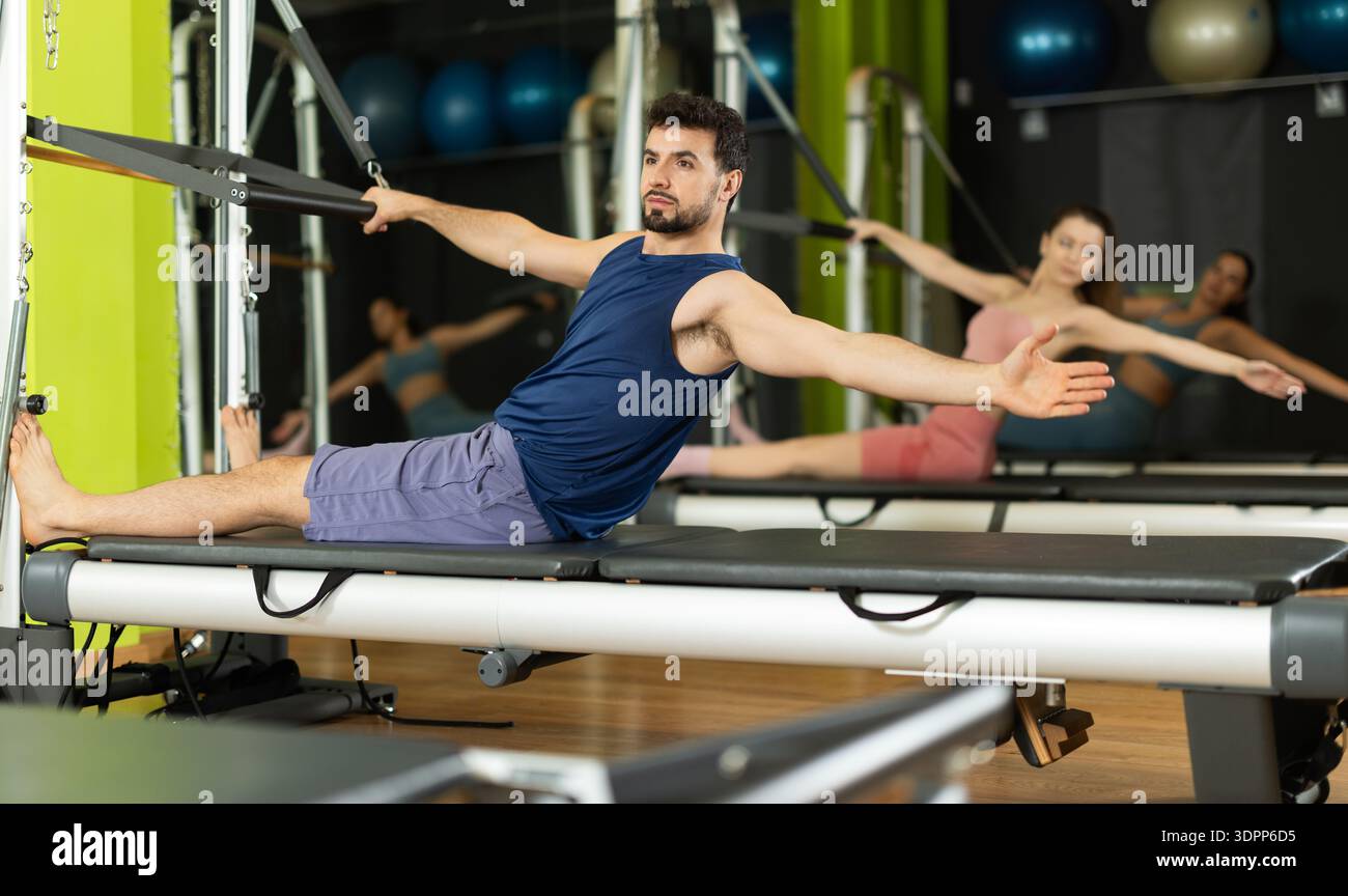 Young man doing abdominal press exercise on pilates reformer Stock Photo