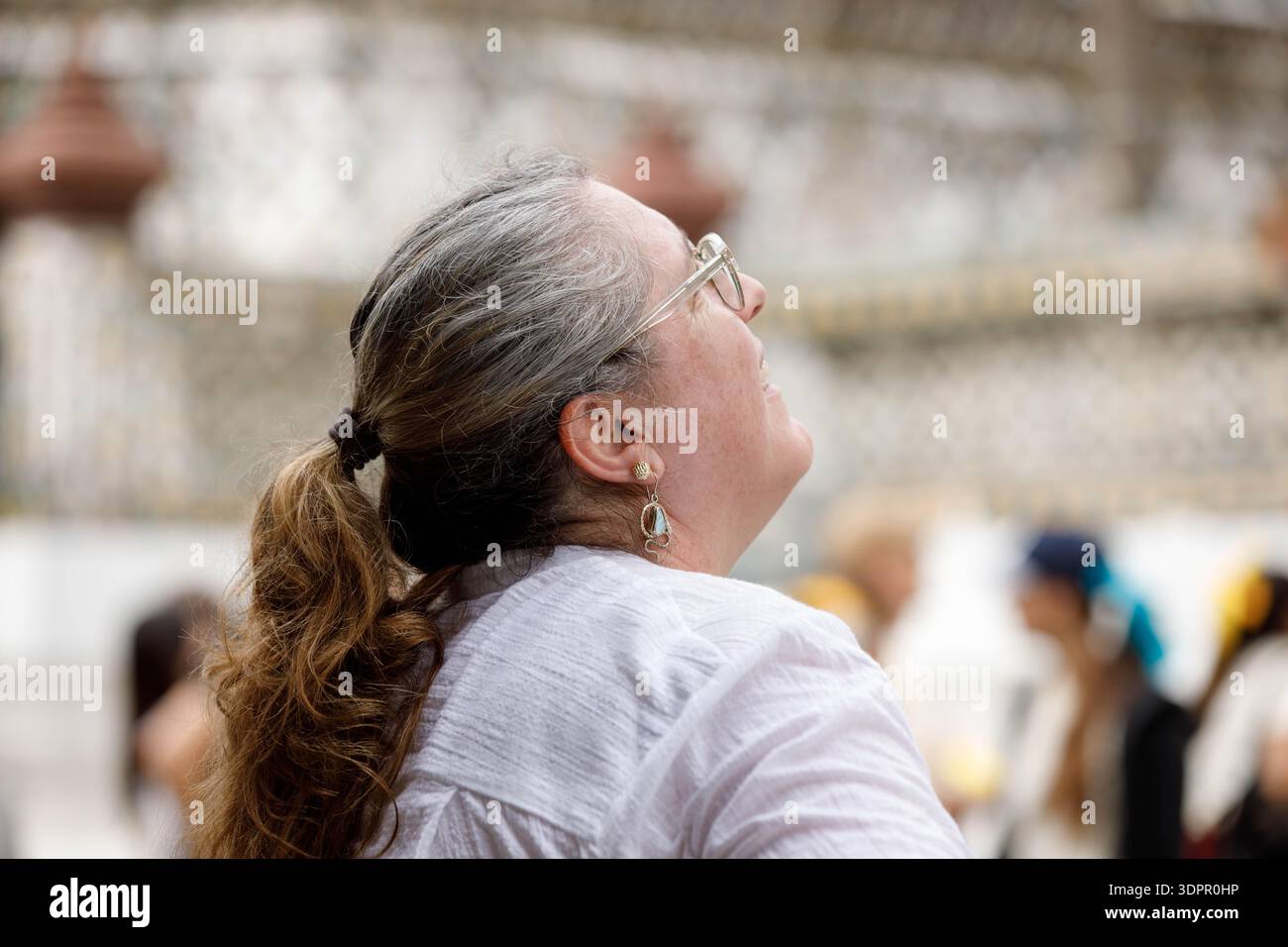 BANGKOK, THAILAND-JAN 21, 2026: Senior female tourist looking up and exploring Wat Thai, side profile Stock Photo