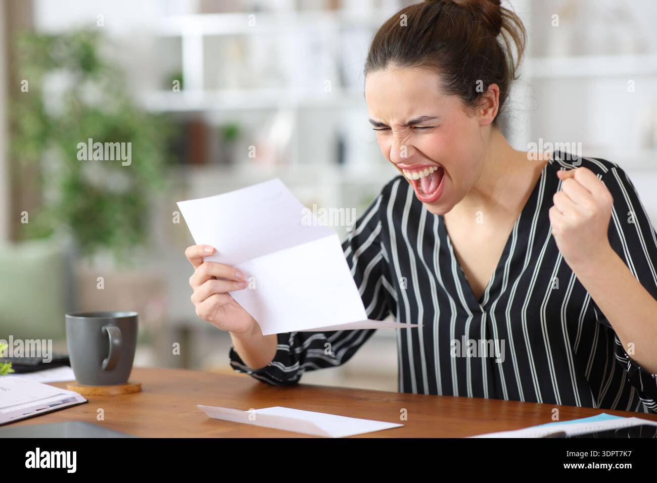 Excited self employed celebrating success holding letter working at home Stock Photo