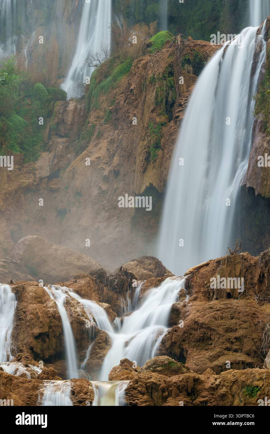 Multi-level waterfall cascades flow over limestone rock formations, with mist rising from the falling water. Stock Photo