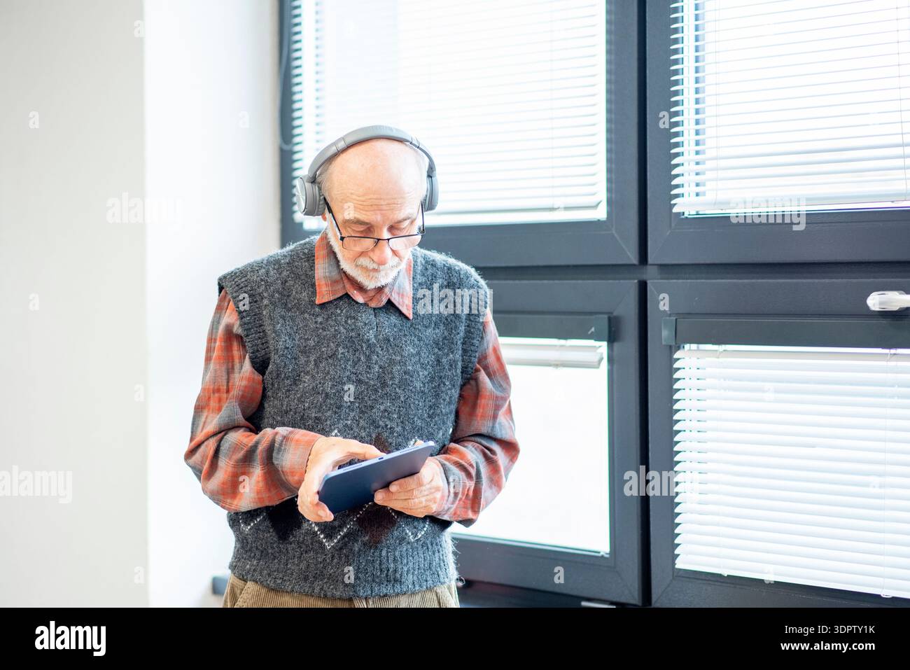 Senior man using tablet and headphones. Stock Photo