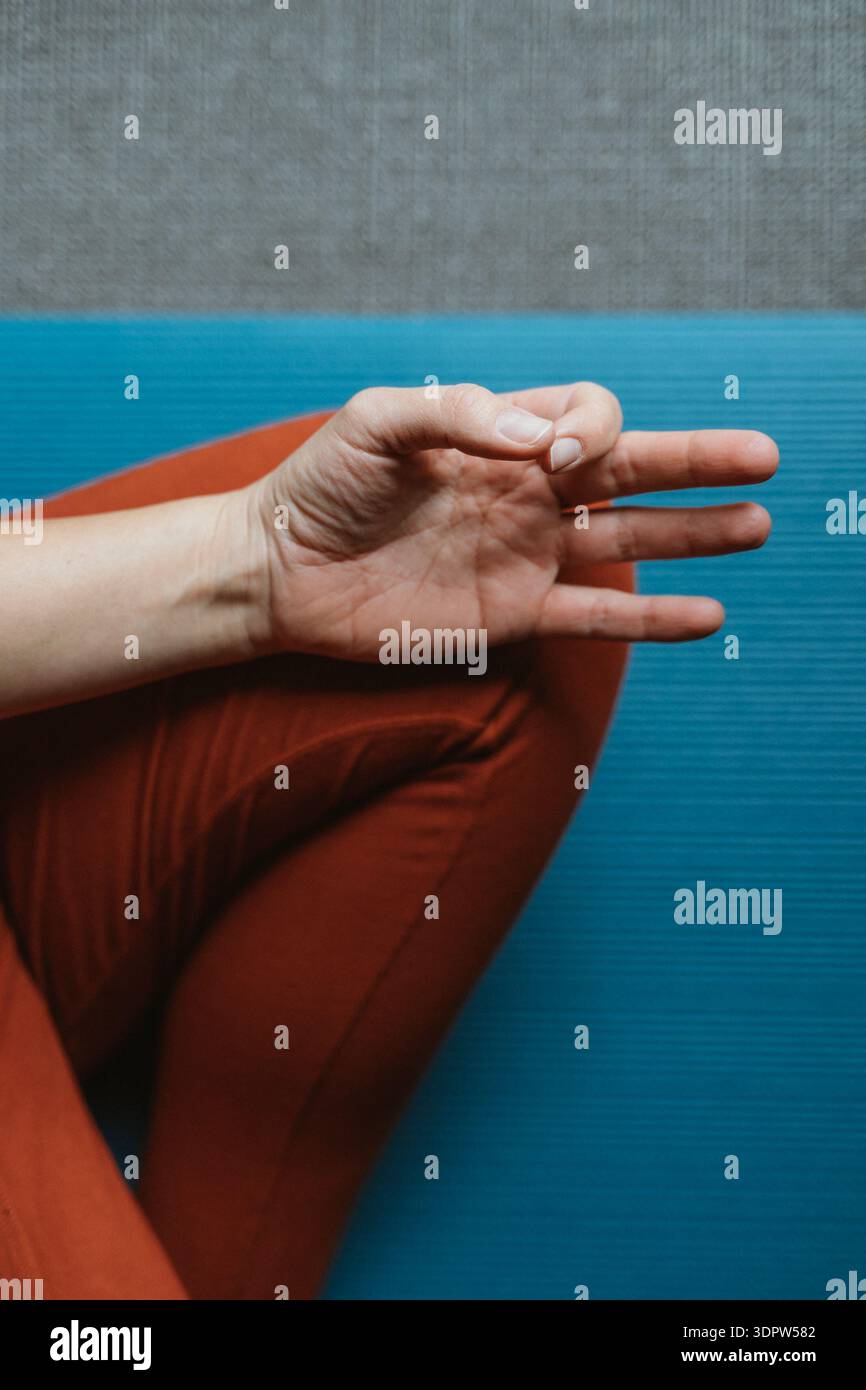 Hand rests in a traditional meditation mudra pose over crossed legs on ...