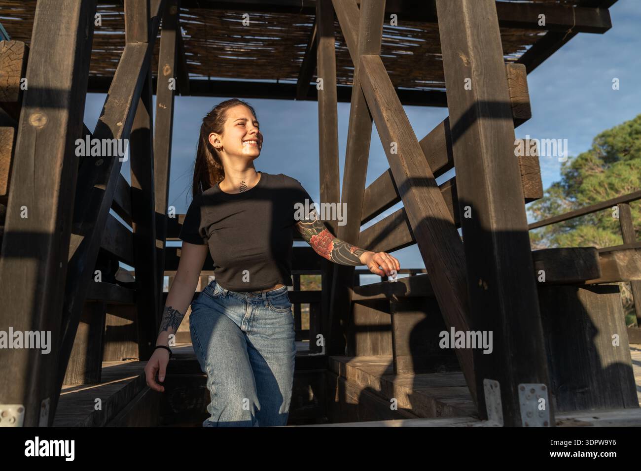 Young woman enjoying sunlight outdoors in wooden structure Stock Photo