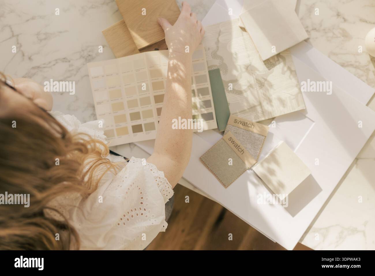 Designer selecting neutral fabric swatch in sunlight Stock Photo