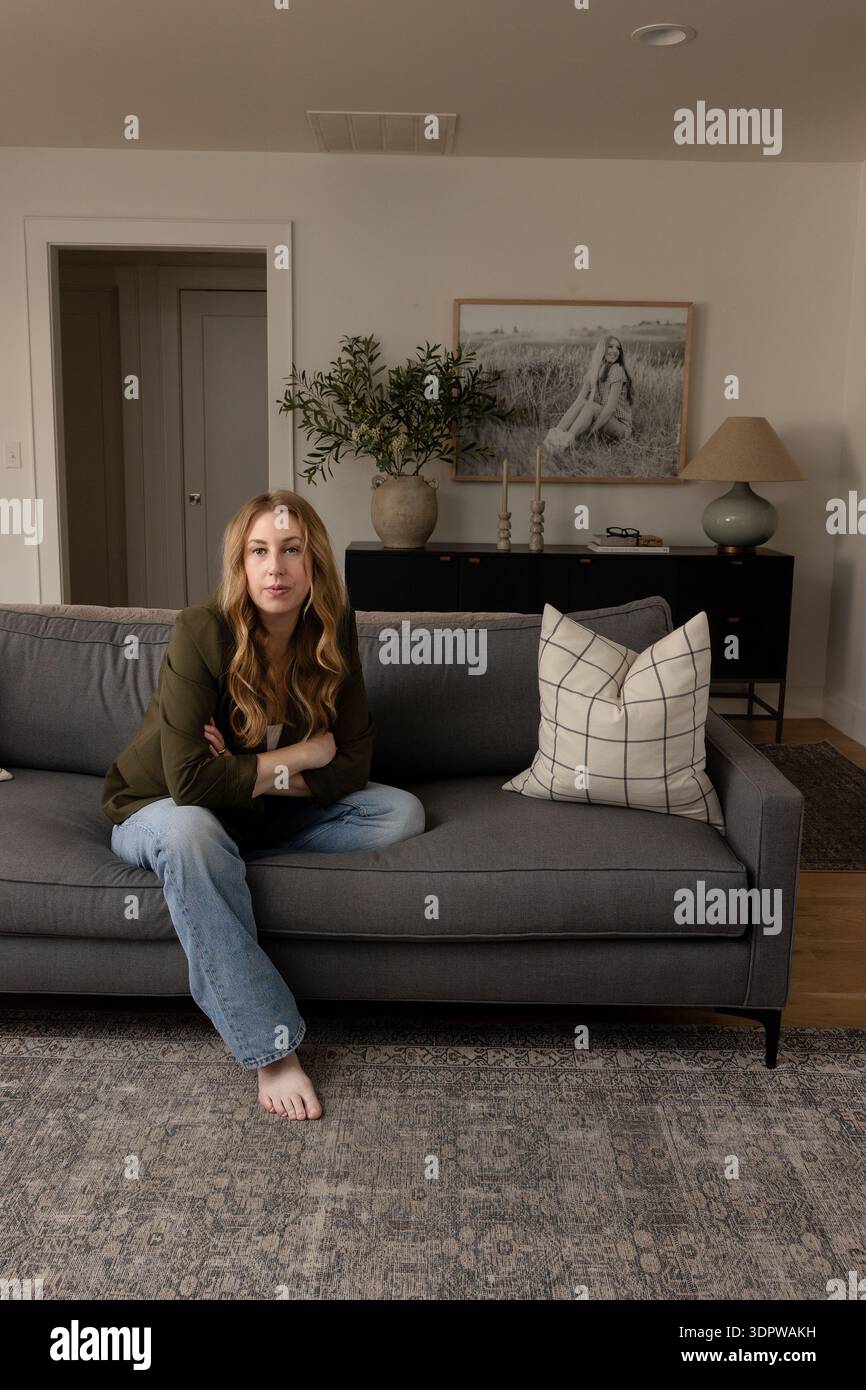 Woman sitting on gray couch hi-res stock photography and images - Alamy