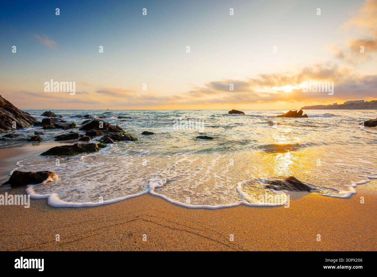 beautiful sunrise over empty sandy beach at the black sea. white foam rolling on to the shore near boulder. perfect summer vacation concept. awesome w Stock Photo