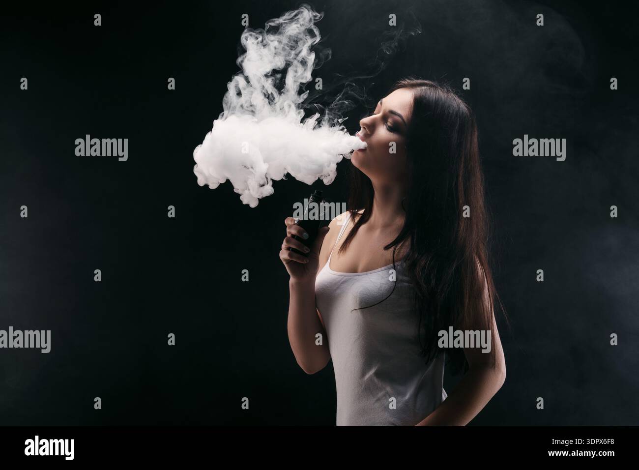 Woman Vaping Smoke in a Dark Room With Dramatic Lighting Stock Photo - Alamy