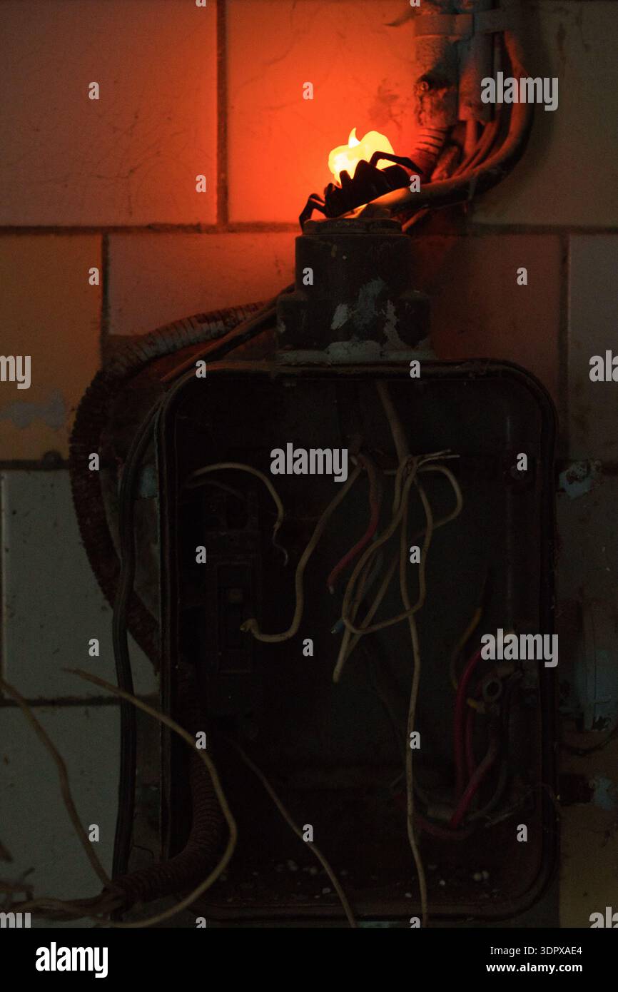 Old fuse box with exposed wires and glowing damaged socket creating dangerous fire hazard indoors Stock Photo