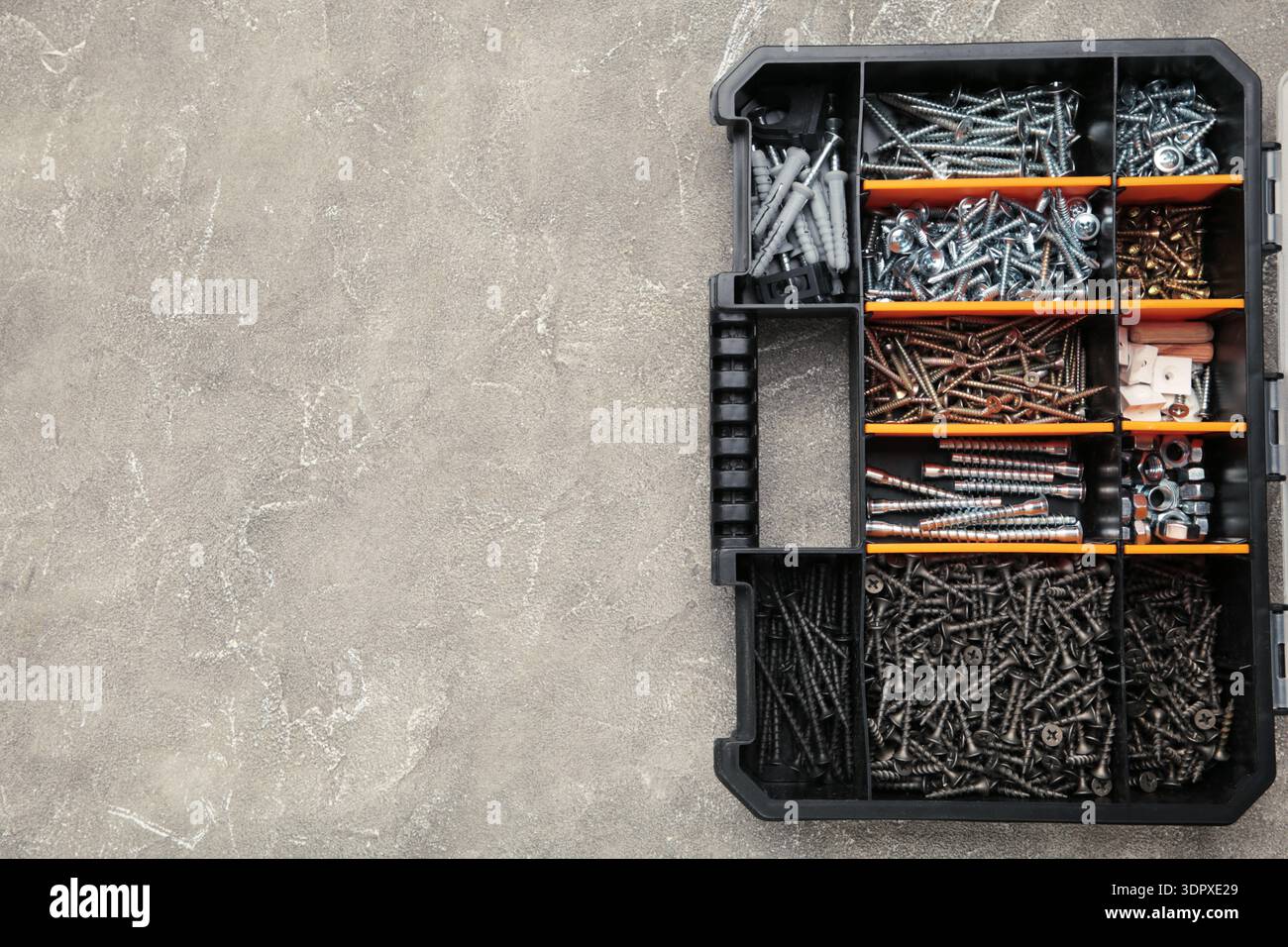 Yellow case with small construction objects on grey background. Space for text Stock Photo