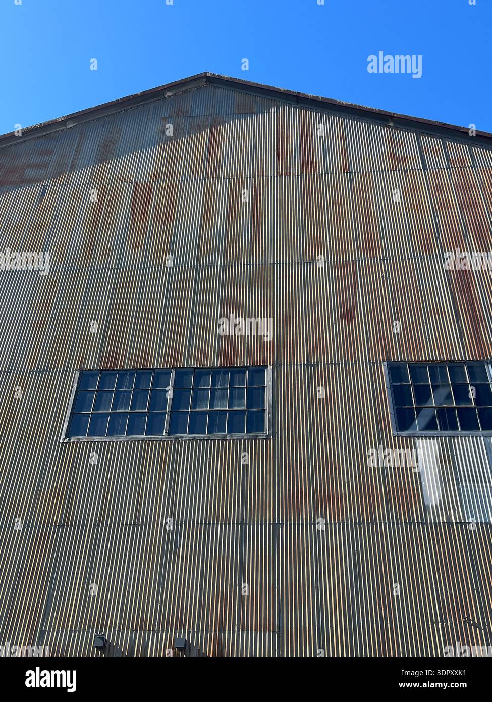 The face of a metal warehouse is lit by the sun, showing off its texture - Smartphone Captured Stock Image